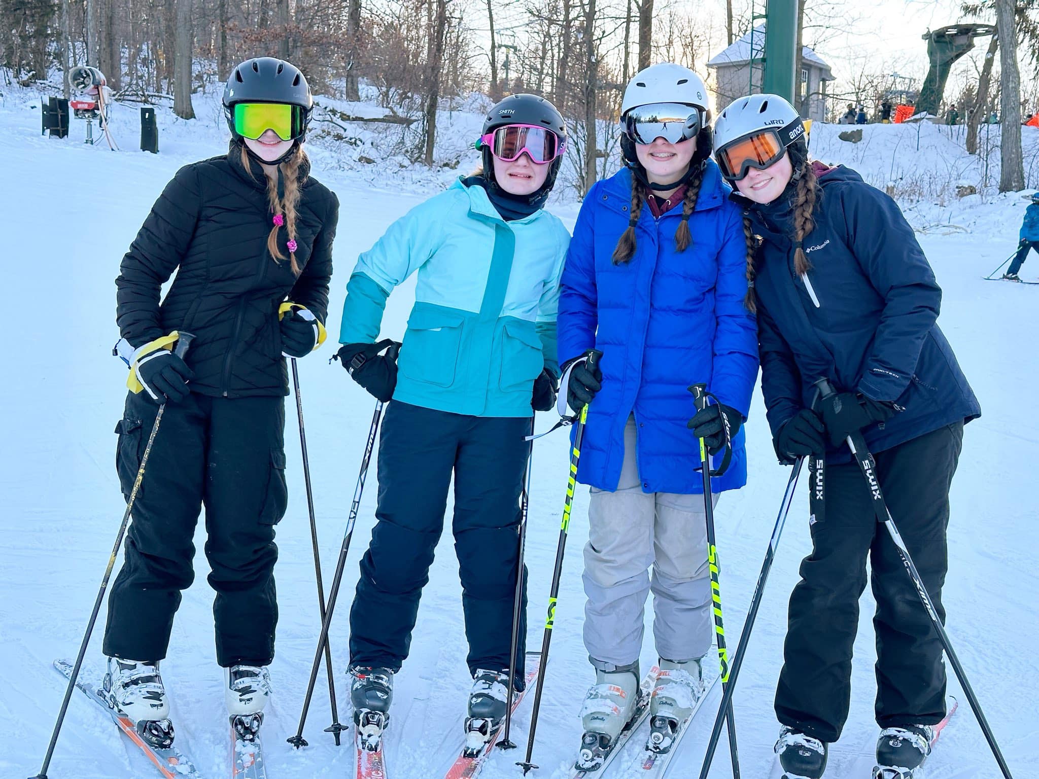 trc ski club group photo a group photo of four girls in ski clothes on skis with a ski slope in the background